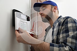 Man installing home security system on white wall in room