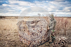 Man installing hunting tent in rural field