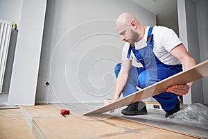 Man installing laminate flooring at home during renovation.