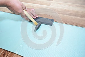 Man installing laminate flooring with insulation board