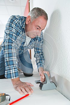 Man installing light laminate flooring in room