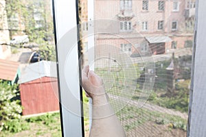 Man is installing the mosquito net on the window. Protection from bugs