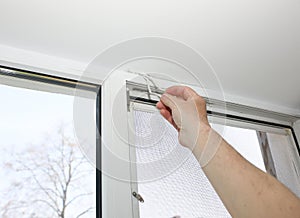 Man is installing the mosquito net on the window. Protection from bugs