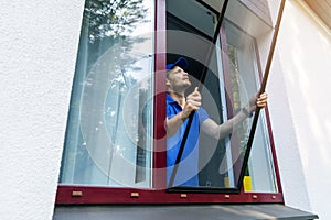 Man installing mosquito net wire mesh on house window