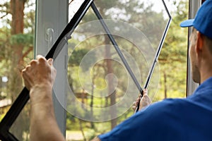 Man installing mosquito net wire mesh on house window