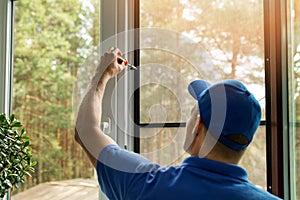 Man installing mosquito net wire screen on house window photo