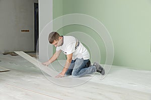 Man installing new laminate flooring in room