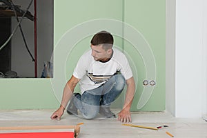 Man installing new laminate flooring in room