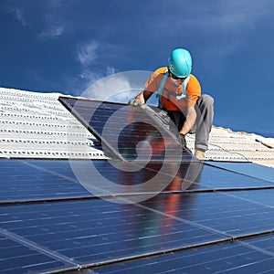 Man installing photovoltaic solar panels to produce green and clean energy