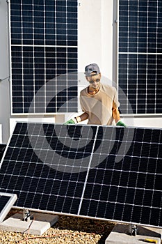 Man installing solar panels on the roof of his house