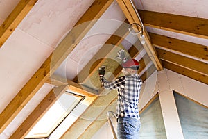 Man installing thermal roof insulation layer - using mineral woo