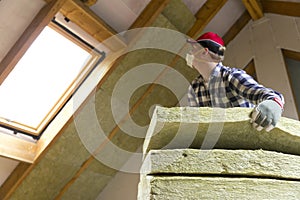 Man installing thermal roof insulation layer - using mineral woo