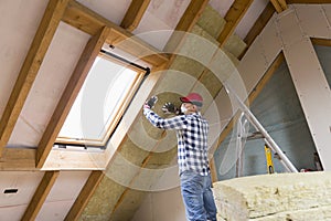 Man installing thermal roof insulation layer - using mineral woo