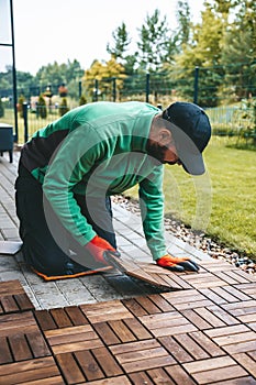 A man installing wood floor planks, building a beautiful terrace