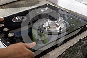 A man installs a built-in glass-ceramic gas stove on a kitchen countertop
