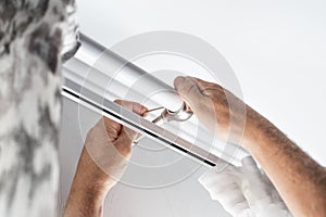 A man installs a curtain for curtains in an apartment. Improvement and decoration of the interior of the house