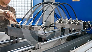 A man installs high pressure hoses into a testing machine. Product quality control photo