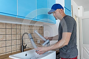 Man installs a new sink in new kitchen. Plumber man fixing kitchen sink