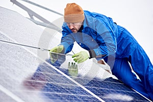 Man installs solar batteries using tools on roof in winter