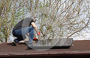 A man installs a solar system to generate electricity on the roof of a garden shed