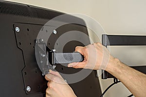 A man installs a TV mount on a wall photo