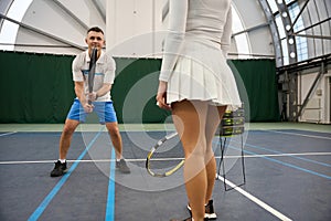 Man instructor preparing woman for competitive tennis training to serve ball