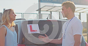 Man instructor shake hands and congratulates the woman on graduating from driving school. Driving school or test.