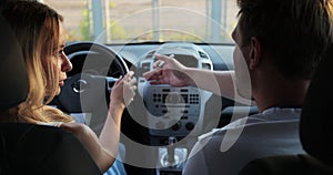 The man instructor teaches student to drive in the car. Backseat view on man and woman in car. Driver courses, exam and