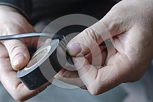 A man is insulating a black electrical wire