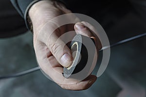 A man is insulating a black electrical wire