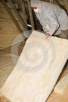 Man insulating a roof or attic of a newly built house with ceramic wool