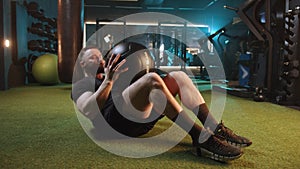 Man with intense workout routine using medicine ball in gym