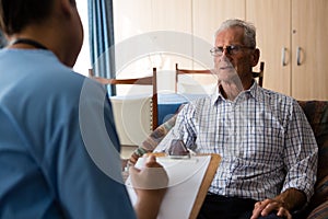 Man interacting with female doctor writing on paper in nursing home