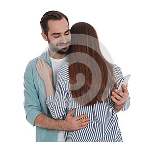 Man interested in smartphone while hugging girlfriend on white background. Relationship problems