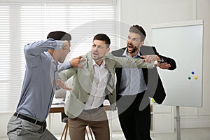 Man interrupting colleagues fight at work