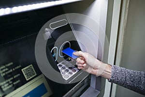 Man introducing a blue credit card to an ATM