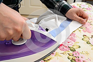 A man ironing clothes on an ironing board
