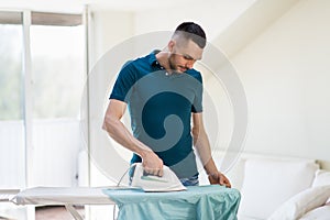 Man ironing shirt by iron at home