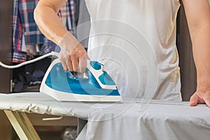 Man IRONING SHIRT ON IRONING BOARD WITH STEAMING IRON.