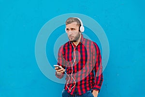 A man isolated on a blue background listens to music on headphones