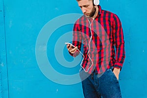 A man isolated on a blue background listens to music on headphones