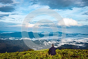 Man isolated feeling the serene nature at hill top with amazing cloud layers in foreground