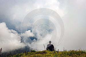 Man isolated feeling the serene nature at hill top with amazing cloud layers in foreground