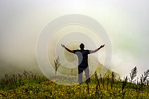 Man isolated feeling the serene nature at hill top with amazing cloud layers in foreground