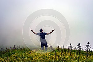 Man isolated feeling the serene nature at hill top with amazing cloud layers in foreground