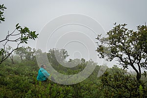 Man isolated feeling the serene nature at hill top with amazing cloud layers in foreground