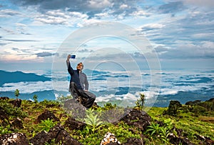 Man isolated taking selfie at hill top with amazing cloud layers in background