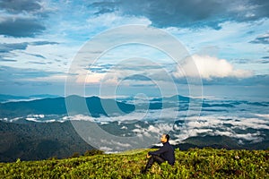 Man isolated watching the serene nature at hill top with amazing cloud layers in background