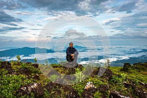 Man isolated watching the serene nature at hill top with amazing cloud layers in background