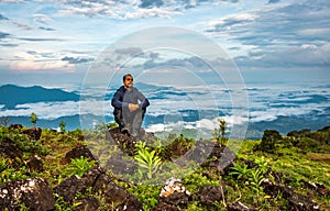 Man isolated watching the serene nature at hill top with amazing cloud layers in background